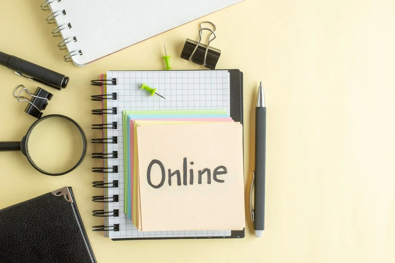 Draufsicht auf eine online geschriebene Notiz zusammen mit bunten kleinen Papierzetteln auf hellem Hintergrund; Notizblock, Job, Stift, Schule, Büro, Geschäft, Geld, Farbe, Arbeit, Heft.